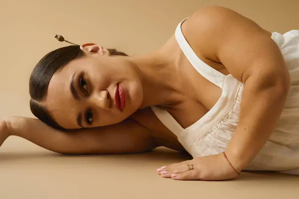 Jeune femme en robe blanche élégante pose gracieusement dans un studio axé sur l'inclusion. — Photo de stock