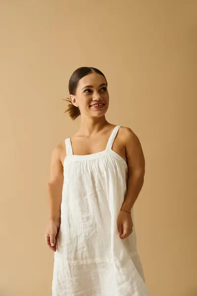 Une jeune femme de petite taille pose gracieusement dans une robe blanche élégante, célébrant l'inclusivité. — Photo de stock