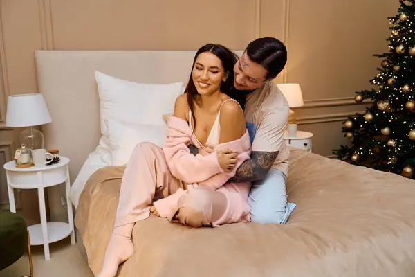 Couple aimant tourne dans la joie sur un lit confortable entouré de décorations de vacances et de chaleur. — Photo de stock