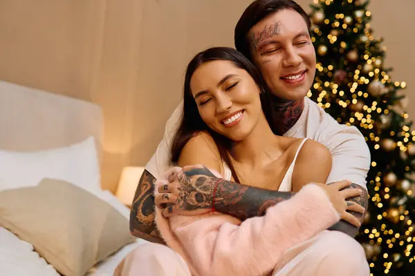 A loving couple enjoying each others warmth, surrounded by a beautifully decorated tree. — Stock Photo