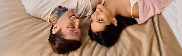 A loving couple lies closely together, laughing and sharing tender moments on a soft bed. — Stock Photo
