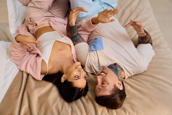 A couple enjoys carefree laughter while lying together on a comfortable bed, radiating love. — Stock Photo