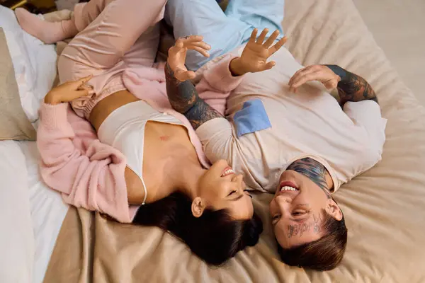 Two young lovers share laughter and affection while relaxing on their comfortable bed. — Stock Photo