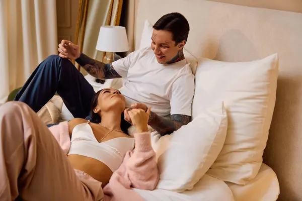 Couple laughs and enjoys intimate bonding while resting on a soft bed surrounded by pillows. — Stock Photo