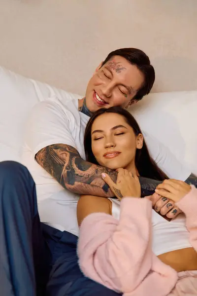 Un jeune couple profite d'un moment tendre ensemble sur un lit confortable, rayonnant d'amour et de bonheur. — Photo de stock