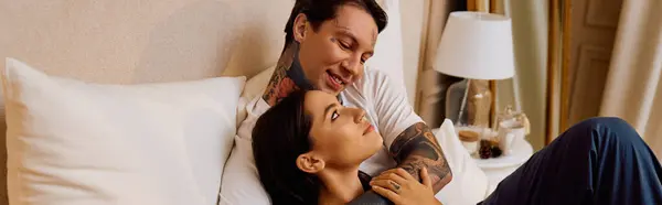 Una coppia condivide momenti teneri in ogni altri abbracciano su un letto morbido, sorridendo amorevolmente. — Foto stock
