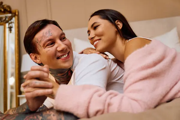 Casal jovem compartilha risos e carinho enquanto relaxa em um ambiente suave e confortável — Fotografia de Stock