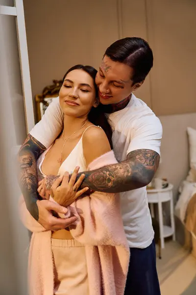 Um jovem casal abraça amorosamente em um quarto acolhedor, desfrutando uns dos outros presença e intimidade. — Fotografia de Stock