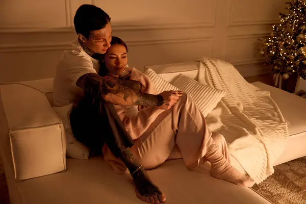 Un jeune couple se détend sur un canapé, partageant chaleur et amour lors d'une soirée d'hiver. — Photo de stock
