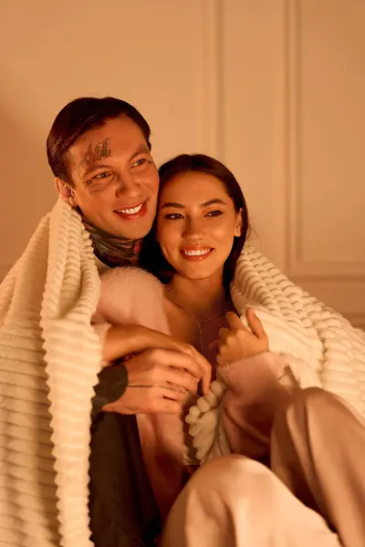 A young couple enjoys a tender embrace, wrapped in a cozy blanket, radiating love and warmth. — Stock Photo