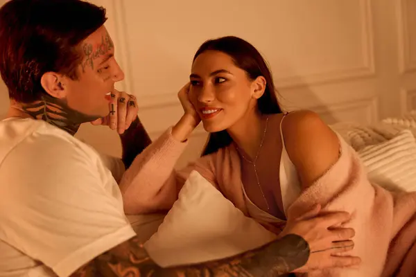 Due persone godono di una conversazione intima mentre si rilassano su un letto, condividendo sorrisi e affetto. — Foto stock