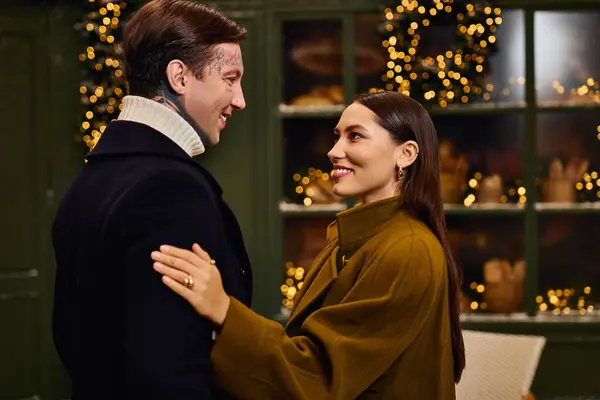 A young couple celebrates their bond while surrounded by warm lights and holiday decorations. — Stock Photo