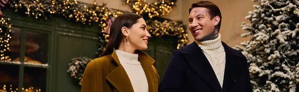 Joyful couple shares a tender moment while walking through a beautifully decorated winter setting. — Stock Photo
