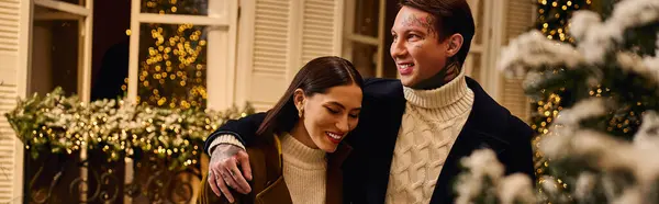 A couple enjoys laughter and joy on a cozy winter evening with holiday decor. — Stock Photo