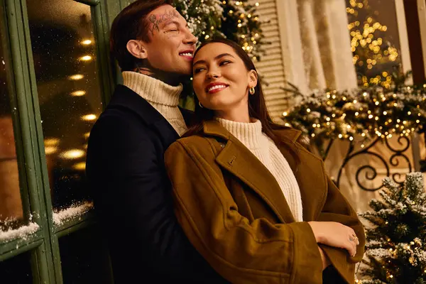 Loving couple enjoys each others company near holiday lights on a chilly evening in winter. — Stock Photo
