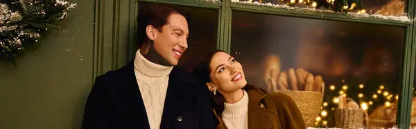A young couple embraces the magic of winter together as they gaze at festive decorations. — Stock Photo