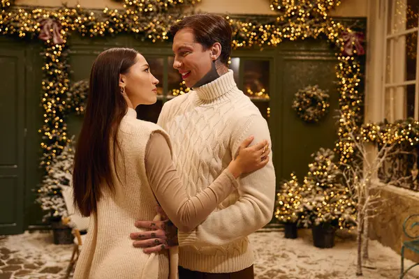 A loving couple embraces each other warmly amidst festive decorations and twinkling lights. — Stock Photo