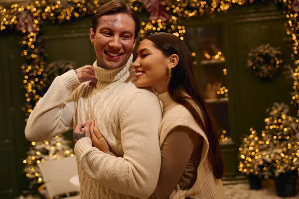 A young couple enjoys a loving moment together surrounded by twinkling lights and holiday decor. — Stock Photo