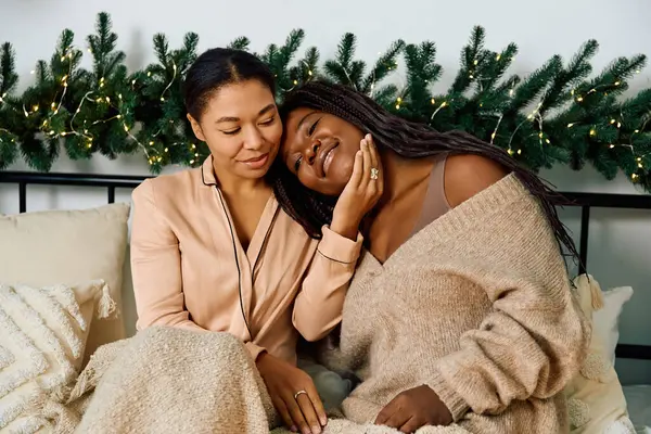 Cuddling together, two women embrace amidst holiday decor, radiating love and joy in winter. — Stock Photo