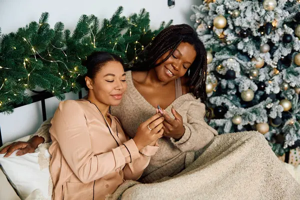 Two women embrace warmth and happiness while enjoying each others company by a festive tree — Stock Photo