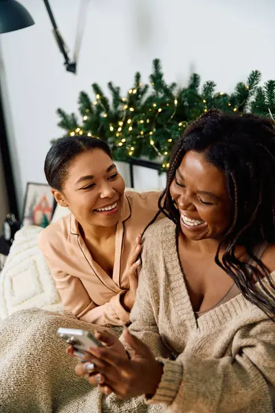 Two women enjoy each others company, laughing and sharing a playful moment near a decorated tree — Stock Photo