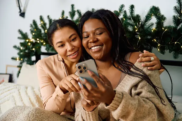 Two women sitting together, enjoying a joyful moment while looking at a mobile device. — Stock Photo