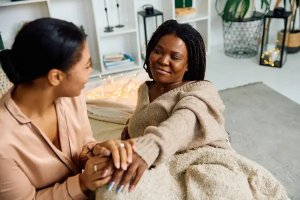 Two loving women share a heartfelt moment while wrapped in a blanket at home. — Stock Photo