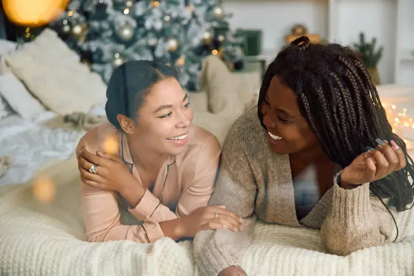 Dos mujeres comparten la risa y el calor en un ambiente acogedor y festivo durante el invierno. - foto de stock