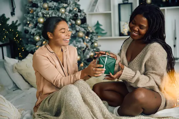 Two women exchange a heartfelt gift in a warm and joyful holiday atmosphere filled with love. — Stock Photo
