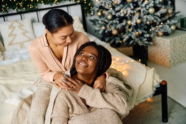Two women share a tender moment in their cozy home, surrounded by festive decorations. — Stock Photo