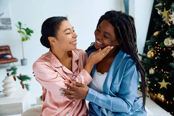 Due donne in comodo pigiama condividono risate e affetto mentre festeggiano insieme. — Foto stock
