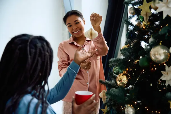 Two joyful women enjoy a festive moment while decorating their holiday tree together — Stock Photo