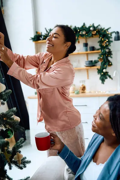 Two women enjoy decorating a cozy space for the holidays while sharing joyful moments. — Stock Photo