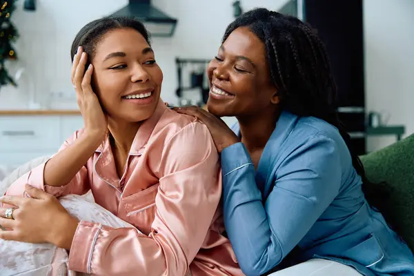 Two women share laughter and affection in their warm pajamas, enjoying a quiet evening at home. — Stock Photo