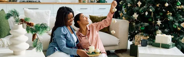 Two women enjoy each others company while decorating a Christmas tree at home. — Stock Photo