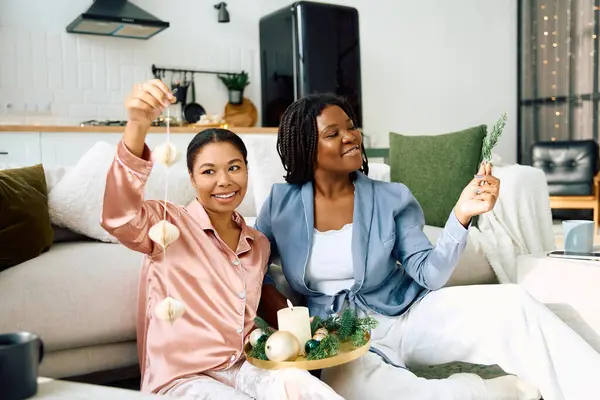 Two women joyfully decorate their cozy living room for the holidays, sharing smiles. — Stock Photo