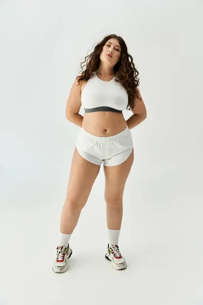 A stylish young plus size woman shines in trendy underwear against a clean, minimal backdrop. — Fotografia de Stock