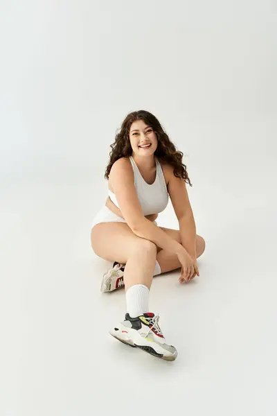 Brightly lit setting features a smiling plus size woman in fashionable underwear and sneakers — Stock Photo