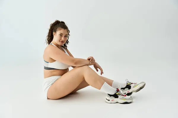 Hermosa mujer de tamaño más exuda encanto mientras posa sin esfuerzo en ropa interior de moda en interiores - foto de stock