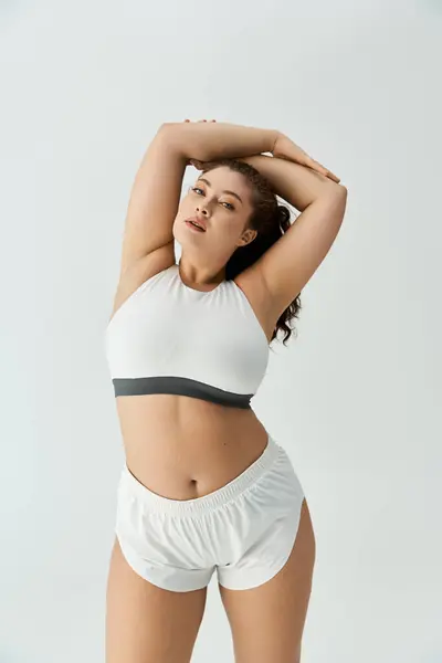 Young woman confidently poses in stylish underwear, embracing her beauty in a bright studio. — Stock Photo