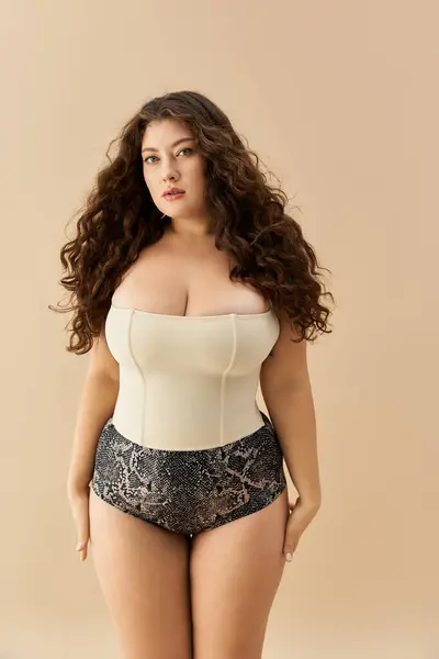 Plus Size Frau präsentiert elegante und modische Unterwäsche vor neutralem Hintergrund. — Stockfoto