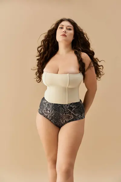 Young plus size woman poses confidently in stylish underwear against a soft, neutral backdrop. — Stock Photo