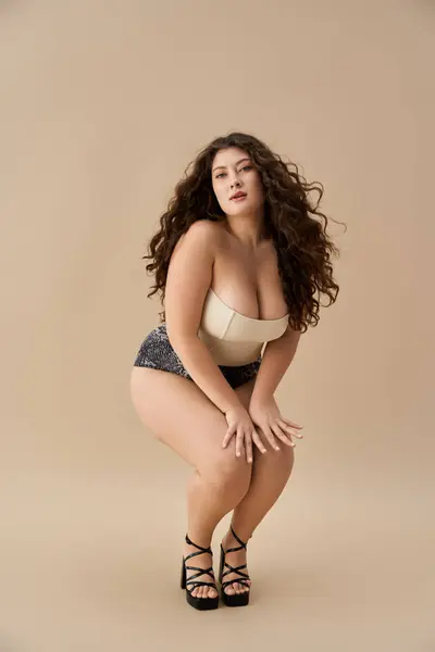 Giovane plus size donna vetrine biancheria intima alla moda con fiducia in uno sfondo neutro — Foto stock