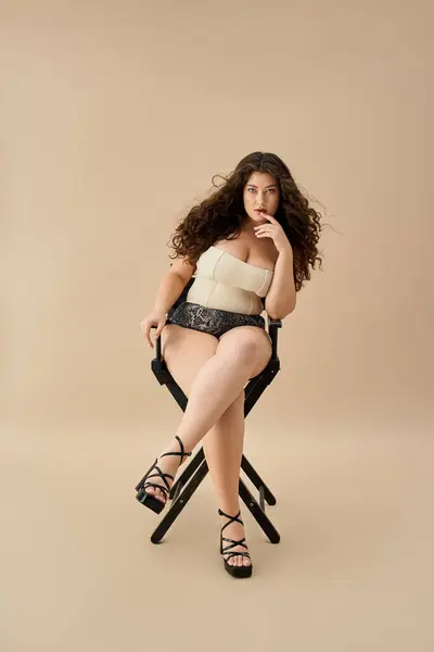 A young plus size woman models fashionable underwear while seated in a chic pose. — Stock Photo
