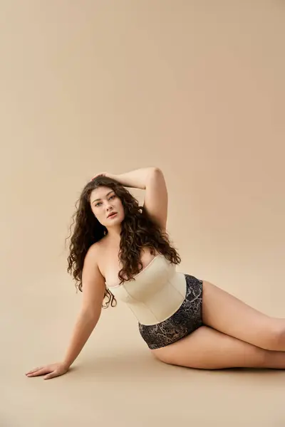 Plus-Size-Frau posiert selbstbewusst in modischer Unterwäsche vor weichem Hintergrund. — Stockfoto