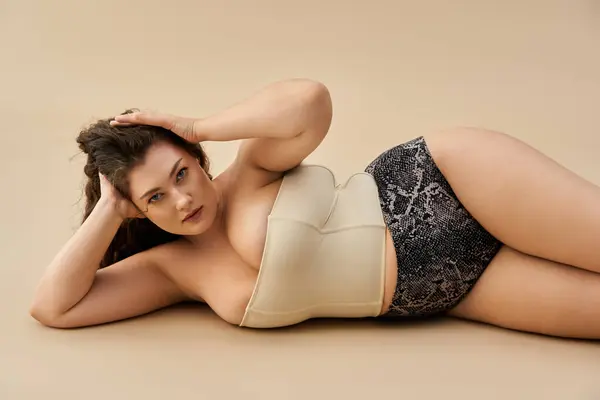 Plus size woman lounges gracefully in fashionable underwear, exuding confidence and beauty. — Stock Photo
