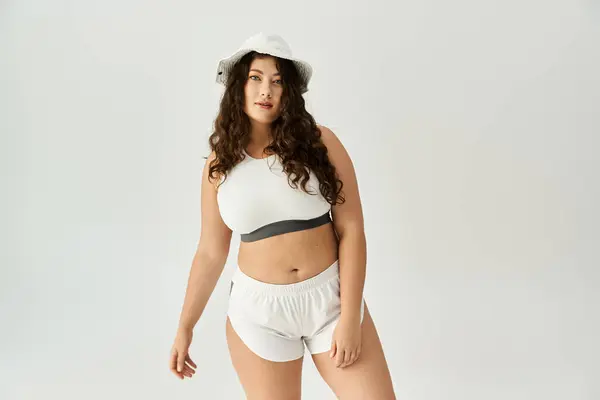 Jeune femme plus la taille met en valeur sa confiance en sous-vêtements à la mode et un chapeau élégant à l'intérieur. — Photo de stock