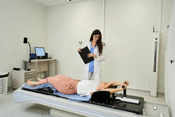 A dedicated female doctor helps a patient feel comfortable on the MRI machine. — Foto stock