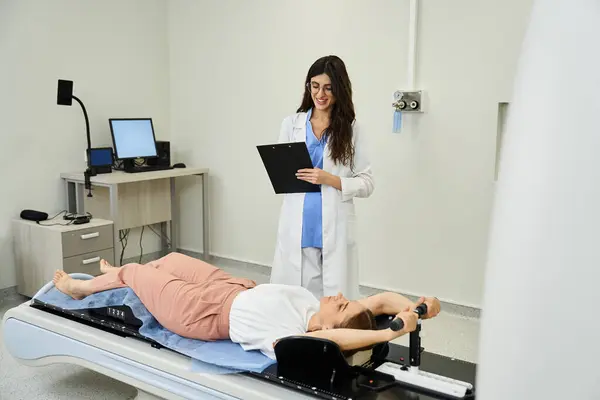 Un médecin en blouse de laboratoire soutient un patient positionné sur une machine d'IRM, assurant confort et soins. — Photo de stock