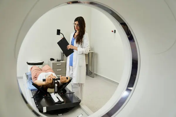 Um médico de jaleco prepara um paciente para uma ressonância magnética em um quarto de hospital. — Fotografia de Stock